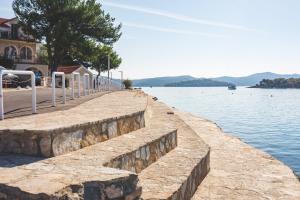 a retaining wall next to a body of water at Apartmani Kristiana in Jezera