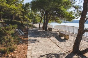 two benches on a path next to a beach at Apartmani Kristiana in Jezera