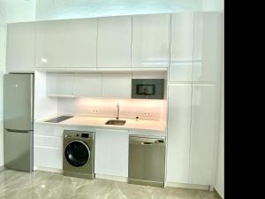 eine weiße Küche mit einer Spüle und einem Geschirrspüler in der Unterkunft Tr2 Aparcamiento Incluido amplio y moderno loft cartuja de sevilla in Sevilla