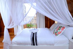 1 dormitorio con 1 cama blanca con dosel en Pelican Lodge & Marina, en Entebbe