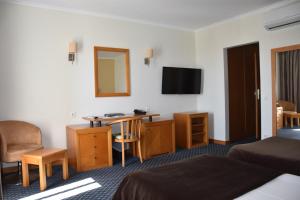 een hotelkamer met een bed, een bureau en een spiegel bij QH Praia de Quiaios in Praia de Quiaos