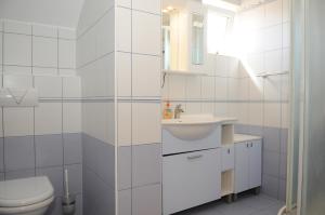 a white bathroom with a toilet and a sink at Apartmani Kristiana in Jezera