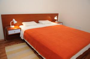 a bedroom with a large bed with an orange blanket at Apartmani Kristiana in Jezera