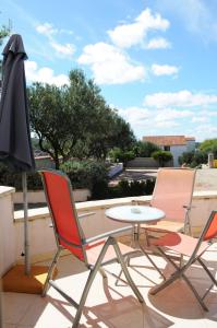 a patio with two chairs and a table and an umbrella at Apartmani Kristiana in Jezera