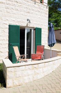 two chairs and an umbrella on a patio at Apartmani Kristiana in Jezera