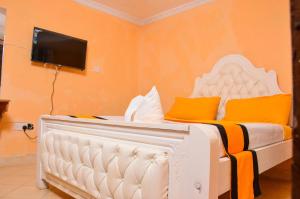 a white bed with orange pillows and a tv on a wall at Consular Resort Meru in Meru