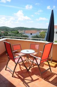 a table and chairs on a balcony with an umbrella at Apartmani Kristiana in Jezera