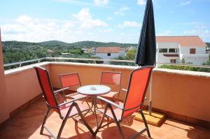 a balcony with three chairs and a table and an umbrella at Apartmani Kristiana in Jezera