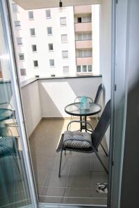 a table and chair on a balcony with a window at Elena apartmani Tuzla in Tuzla