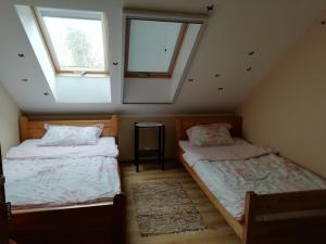 two beds in a attic room with two windows at Gospodarstwo Agroturystyczne Kamez in Szczytno