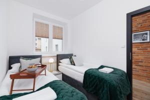 pokój hotelowy z dwoma łóżkami i stołem w obiekcie Apartments Osiedle Szkolne Cracow by Noclegi Renters w Krakowie