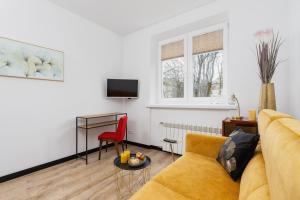 salon z żółtą kanapą i czerwonym krzesłem w obiekcie Apartments Osiedle Szkolne Cracow by Noclegi Renters w Krakowie