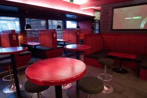 un restaurante con mesas rojas y taburetes en Hotel Kiteenhovi en Kitee