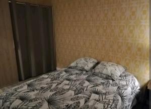 an unmade bed in a bedroom with a wall at Joli T2 près de Rennes in Vezin-le-Coquet