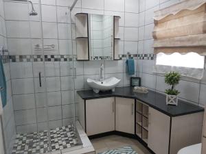 La salle de bains est pourvue d'un lavabo et d'un miroir. dans l'établissement Genie's Nest Ooie 3, à Pretoria