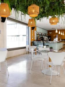 um restaurante com mesas brancas, cadeiras e luzes em Daniya Alicante em Alicante