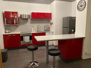 una cucina con armadi rossi e un bancone con sgabelli di Logement calme et spacieux avec terrasses a Le Havre