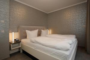 Schlafzimmer mit einem Bett mit weißer Bettwäsche und Kissen in der Unterkunft Linden-Palais Wohnung 33 in Heiligendamm