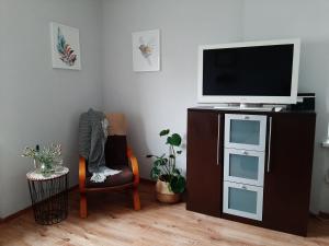 ein Wohnzimmer mit einem TV und einem Stuhl in der Unterkunft Apartament Oksywska Przystań in Gdynia