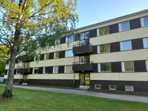 un edificio de apartamentos con un árbol delante de él en Retroyksiö, en Björkboda