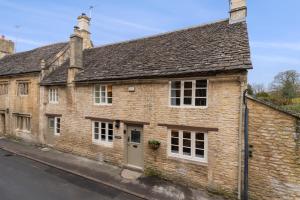 um velho edifício de tijolos ao lado de uma rua em Farthingdales em Burford