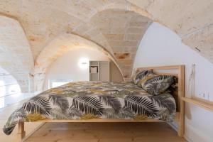 Ce lit se trouve dans un dortoir doté d'un mur en pierre. dans l'établissement Fico apartment, à San Vito dei Normanni