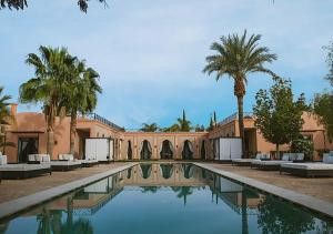ein Haus mit einem Pool mit Palmen in der Unterkunft DAR JMEL in Marrakesch