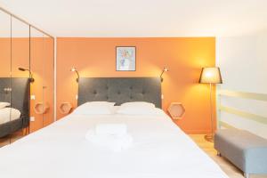 a bedroom with a large white bed and orange walls at Les Nuances de Julien in Nancy