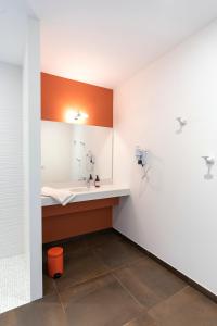 een ziekenhuiskamer met een wastafel en oranje en witte muren bij HOTEL LE 25 in Andernos-les-Bains