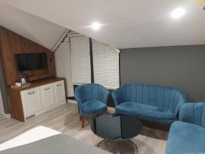 a living room with two blue chairs and a tv at White Golden Suite Hotel in Trabzon