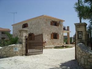 a stone house with a gate and a fence at Villa Karissa - Zante in Vasilikos