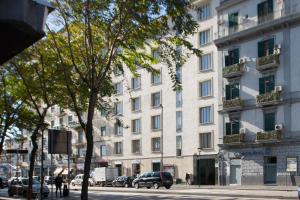 wysoki biały budynek z samochodami zaparkowanymi przed nim w obiekcie Corso Novara 5 Design Apartments w mieście Neapol