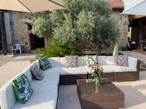 a white couch with pillows and a table and an umbrella at maison de vacances Mont de Marsan in Lucbardez-et-Bargues