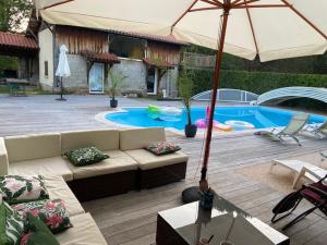a patio with a couch and an umbrella next to a pool at maison de vacances Mont de Marsan in Lucbardez-et-Bargues +9 photos