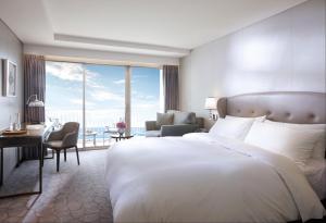 a bedroom with a large bed and a living room with a view at Paradise Hotel Busan in Busan