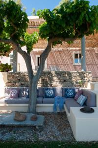 un sofá sentado bajo un árbol al lado de un edificio en Montofoli Wine Estate, en Caristo