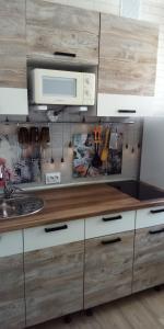 a kitchen with wooden cabinets and a microwave at Apartment in Kamchatka on Abelya in Petropavlovsk-Kamchatskiy