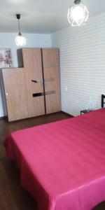 a bedroom with a pink bed and a wooden cabinet at Apartment in Kamchatka on Abelya in Petropavlovsk-Kamchatskiy