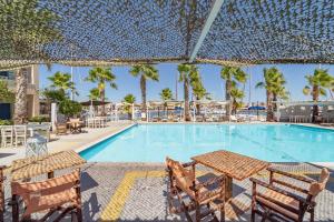 una piscina con sillas, una mesa y un patio en Ianos Hotel, en Lefkada