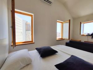 a bedroom with two pillows on a bed with windows at Brand new apt W balcony & perfect seaview at center in Hvar