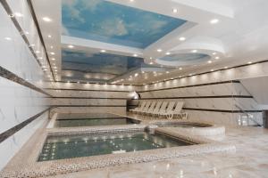 einen Pool mit Wasser in einem Zimmer mit Stühlen in der Unterkunft Hotel Bellavista & Spa in Bukowel