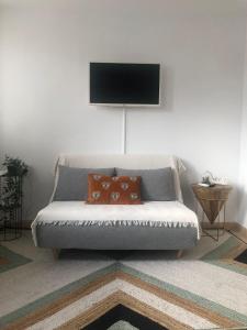 a living room with a couch with a television on the wall at Apartmento studio boho a 1 minuto del puerto y la playa! in Jávea