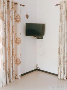 a flat screen tv in a room with curtains at Romaclan Villa in Midigama