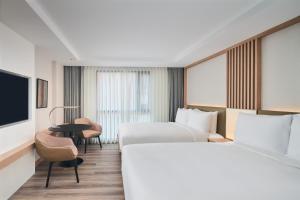 a hotel room with two beds and a tv at Courtyard by Marriott North Pattaya in North Pattaya