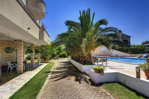 ein Haus mit einer Palme neben einem Pool in der Unterkunft Apartments Villa Delia in Medulin