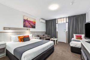a hotel room with two beds and a television at Comfort Inn Glenelg in Adelaide