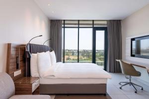 a bedroom with a bed and a desk and a window at Radisson Blu Hotel & Residence Maputo in Maputo