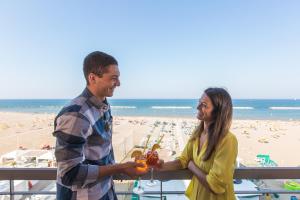 Un hombre y una mujer de pie en un balcón en la playa. en Giovanna Regina Hotel, en Gabicce Mare