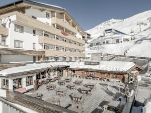 a balcony of a hotel with tables and chairs in the snow at Sporthotel Olymp in Hochgurgl