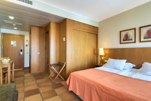 
a hotel room with a bed, chair, and table at Four Views Monumental Lido in Funchal
